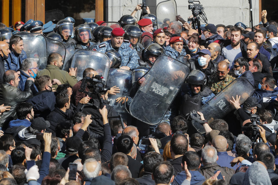 People argue with police during a protest against an agreement to halt fighting over the Nagorno-Karabakh region, in Freedom Square in Yerevan, Armenia, Wednesday, Nov. 11, 2020. Thousands of people flooded the streets of Yerevan once again on Wednesday, protesting an agreement between Armenia and Azerbaijan to halt the fighting over Nagorno-Karabakh, which calls for deployment of nearly 2,000 Russian peacekeepers and territorial concessions. Protesters clashed with police, and scores have been detained. (AP Photo/Dmitri Lovetsky)