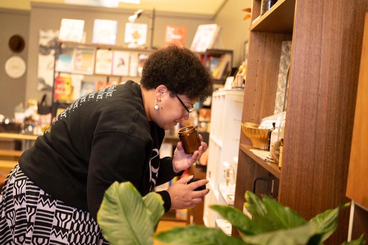Owner Tiffany Blackman adjusts candle displays at Bread & Basket in downtown Battle Creek on Tuesday, Nov. 14, 2023.
