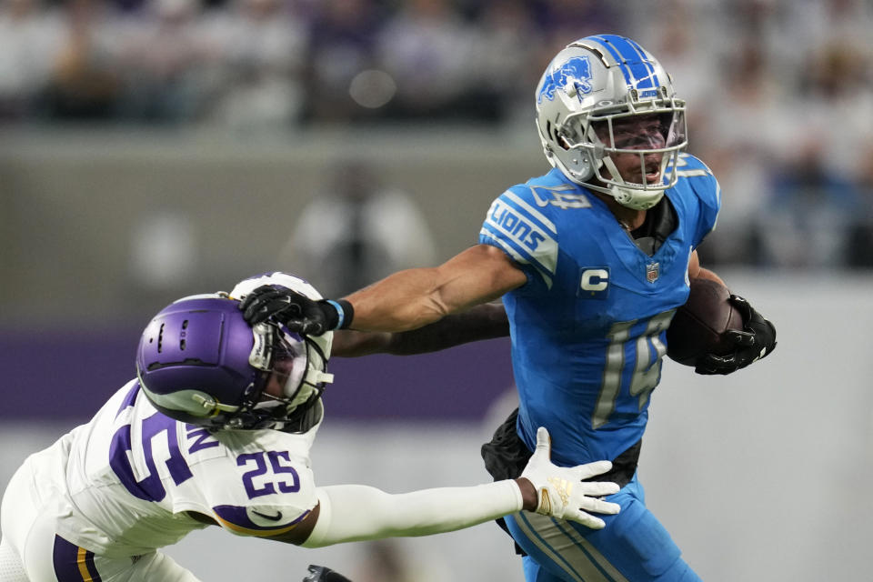 Detroit Lions wide receiver Amon-Ra St. Brown (14) breaks a tackle by Minnesota Vikings safety Theo Jackson (25) during the second half of an NFL football game, Sunday, Dec. 24, 2023, in Minneapolis. The Lions won 30-24. (AP Photo/Abbie Parr)