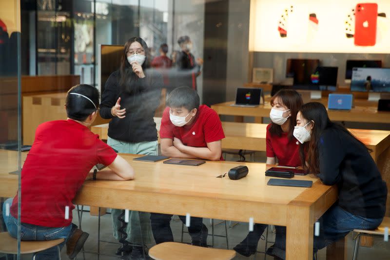 People wear face masks as they listen to a presentation in an Apple Store in the Sanlitun shopping district in Beijing