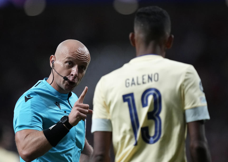 FILE - Referee Szymon Marciniak, left, talks with Porto's Galeno during the Champions League Group B soccer match between Atletico Madrid and Porto at the Metropolitano stadium in Madrid, Spain, on Sept. 7, 2022. Polish soccer referee Szymon Marciniak has apologized for speaking at a business event tied to a far-right politician and was confirmed by UEFA to officiate next week's Champions League final. Marciniak’s appointment for the game between Manchester City and Inter Milan on June 10 was at risk. (AP Photo/Bernat Armangue, File)