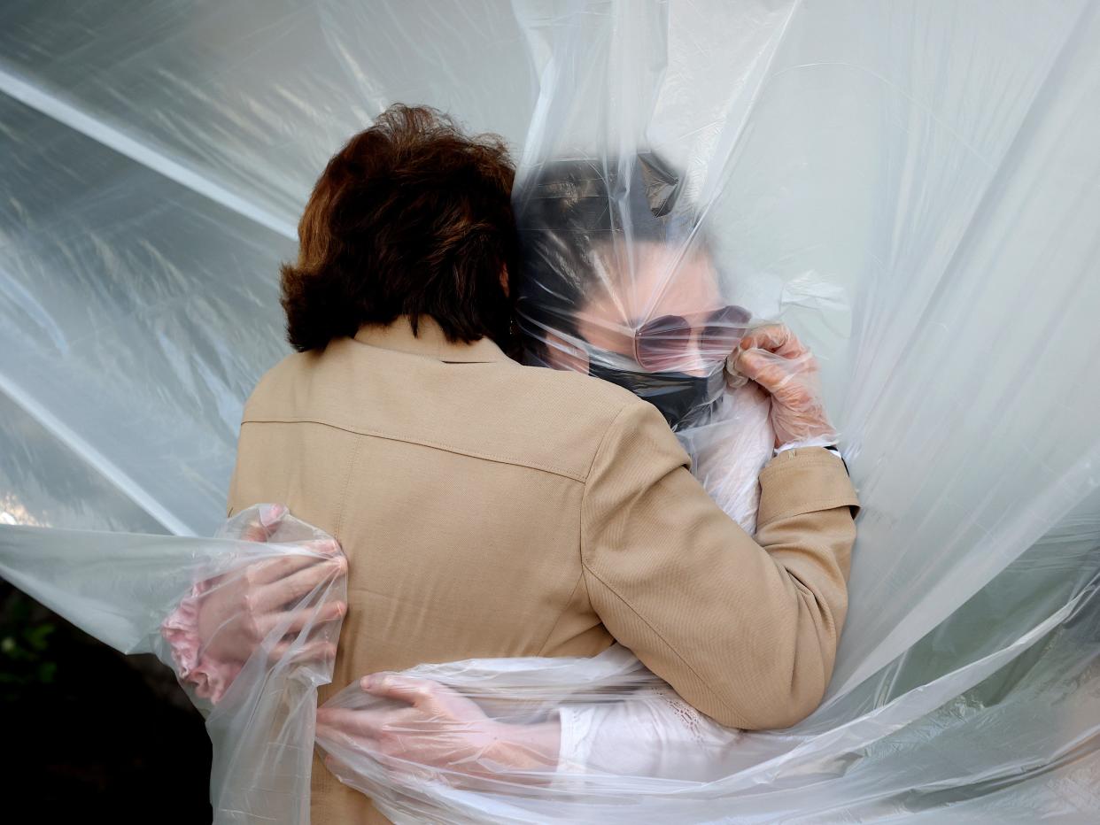 Olivia Grant (R) hugs her grandmother, Mary Grace Sileo through a plastic drop cloth hung up on a homemade clothes line during Memorial Day Weekend on May 24, 2020 in Wantagh, New York. (Al Bello:Getty Images)