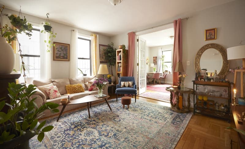 Sunny living room in Brooklyn apartment with cream colored sofa and small armchair in corner.