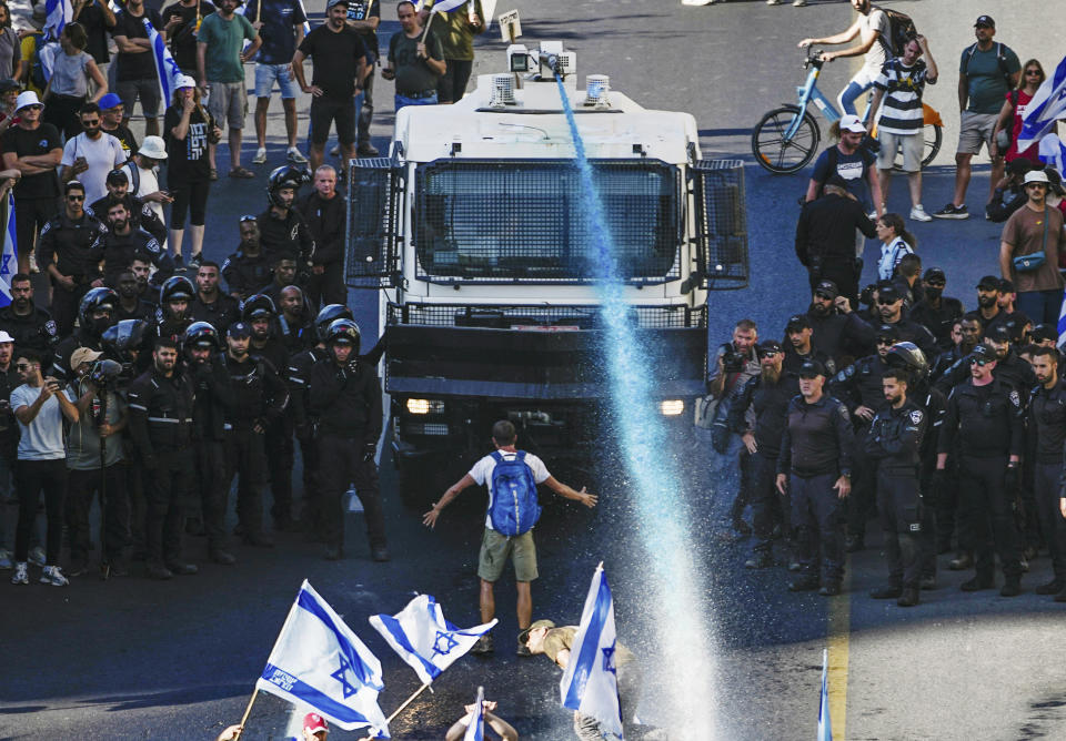 FILE - A person stands in front of an Israeli police water cannon being used to disperse demonstrators blocking a road during a protest against plans by Prime Minister Benjamin Netanyahu's government to overhaul the judicial system, in Jerusalem, Monday, July 24, 2023. Netanyahu's government, made up of ultranationalist and ultra-religious parties, was formed last year and immediately pressed ahead with a contentious plan to reshape the country's judiciary. (AP Photo/Ariel Schalit, File)