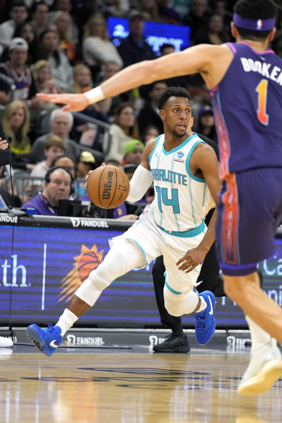 Charlotte Hornets guard Ish Smith (14) drives on Phoenix Suns guard Devin Booker during the first half of an NBA basketball game, Friday, Dec. 29 2023, in Phoenix. (AP Photo/Rick Scuteri)