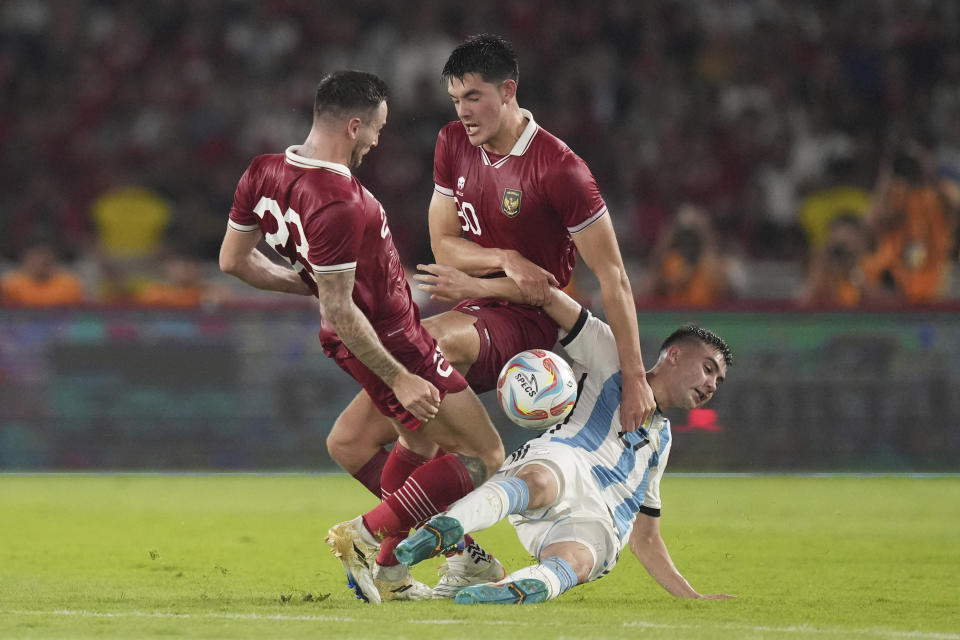 Argentina's , bottom, battles for the ball against Indonesia's Marc Anthony Klok, left, and Elkan Baggott during their friendly soccer match at Gelora Bung Karno Main Stadium in Jakarta, Indonesia, Monday, June 19, 2023. (AP Photo/Tatan Syuflana)