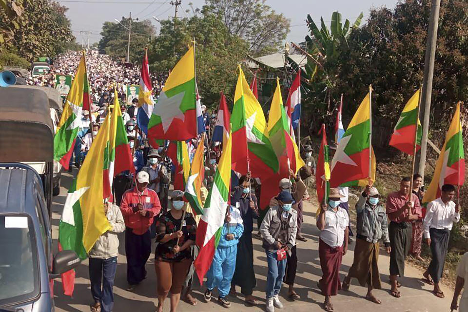 In this image provided by the Military True News Information Team, supporters of the military government wave Myanmar flags as they lead a crowd during a rally on Tuesday, Feb. 1, 2022 in Naypyitaw, Myanmar. Opponents of military rule in Myanmar on Tuesday marked the one-year anniversary of the army's seizure of power with a nationwide strike to show their strength and solidarity amid concern about what has become an increasingly violent contention for power. (Military True News Information Team via AP)