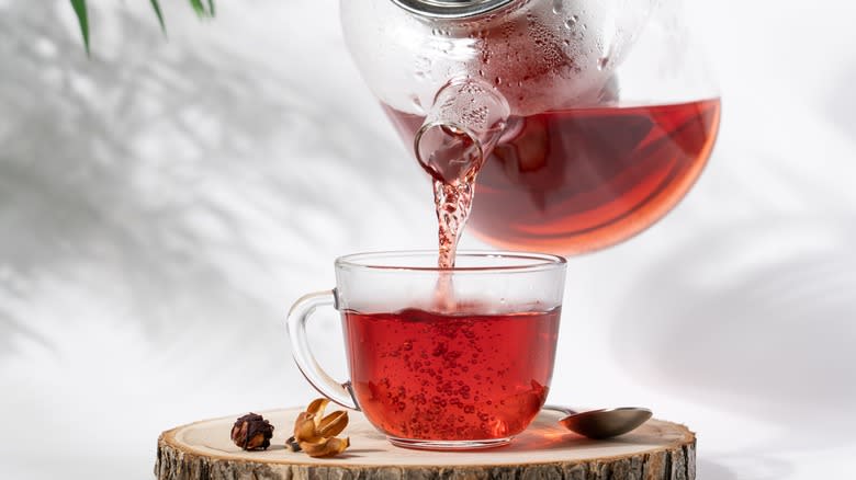 Glass teapot pouring red tea