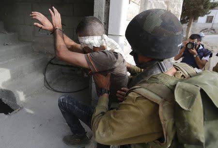 An Israeli soldier detains a Palestinian during an operation to locate three Israeli teens near the West Bank City of Hebron June 21, 2014. REUTERS/ Mussa Qawasma
