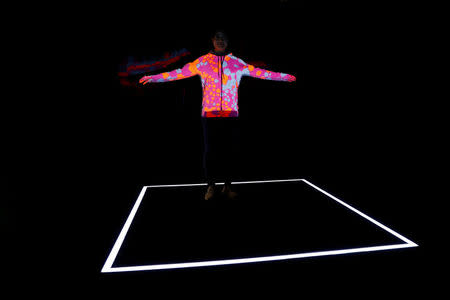 A staff member uses a projector to display the knitting pattern at the Adidas Knit for You store in Berlin, Germany March 7, 2017. Picture taken March 7, 2017. REUTERS/Fabrizio Bensch