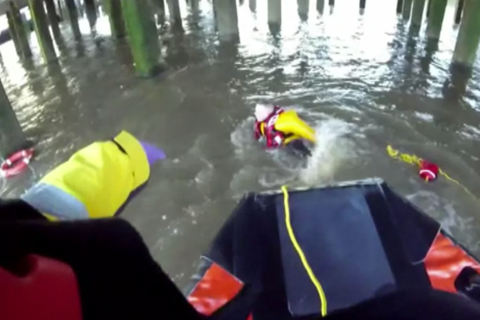 A Tower Lifeboat crew member jumps into the River Thames to rescue a drowning man. (Tower RNLI)