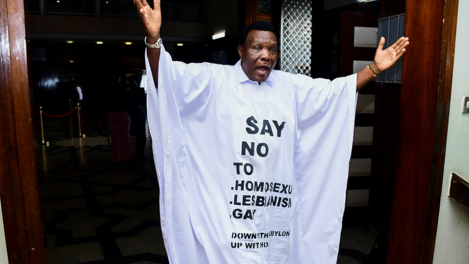 El diputado ugandés John Musira, vestido con un traje antigay, gesticula mientras abandona el hemiciclo durante el debate del proyecto de ley contra la homosexualidad.