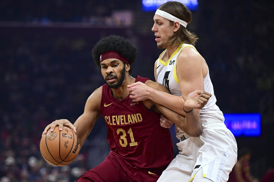 Cleveland Cavaliers center Jarrett Allen is defended by Utah Jazz forward Kelly Olynyk during the first half of an NBA basketball game Wednesday, Dec. 20, 2023, in Cleveland. (AP Photo/David Dermer)