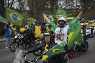 Supporters of Brazilian President Jair Bolsonaro wave Brazilian flags during a motorcycle campaign rally in Pocos de Caldas, Brazil, Friday, Sept. 30, 2022. Brazil’s Oct. 2 presidential election is being contested by 11 candidates but only two stand a chance of reaching a runoff: former President Luiz Inacio Lula da Silva and incumbent Jair Bolsonaro. (AP Photo/Victor R. Caivano)