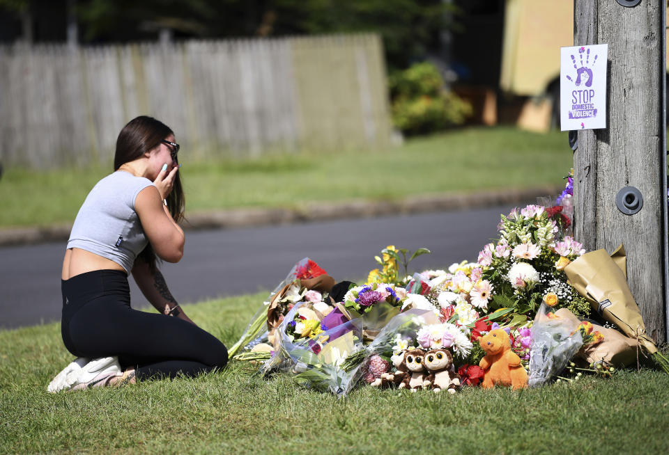 Korri Loader, a friend of the victims of a car fire, sits at a makeshift memorial, Thursday, Feb. 20, 2020, near the scene of a car fire which claimed the lives of a mother and her three young children in Brisbane, Australia. Hannah Baxter, 31, and her children Aaliyah, 6, Lainah, 4, and Trey, 3, died after their car was set alight on a street in suburban Brisbane on Wednesday morning. (Dan Peled/AAP Image via AP)