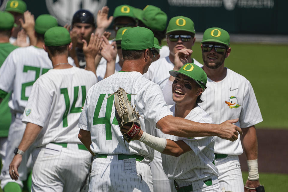 Oregon head coach Mark Wasikowski, left, hugs right fielder Rikuu Nishida, right, as the team celebrates their 5-4 win against Xavier after an NCAA college baseball tournament regional game Friday, June 2, 2023, in Nashville, Tenn. (AP Photo/George Walker IV)