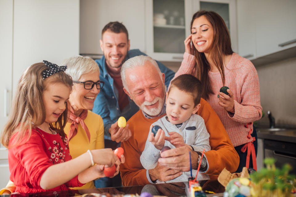 Happy old couple smiling when coloring Easter eggs with children and grandchildren conversations