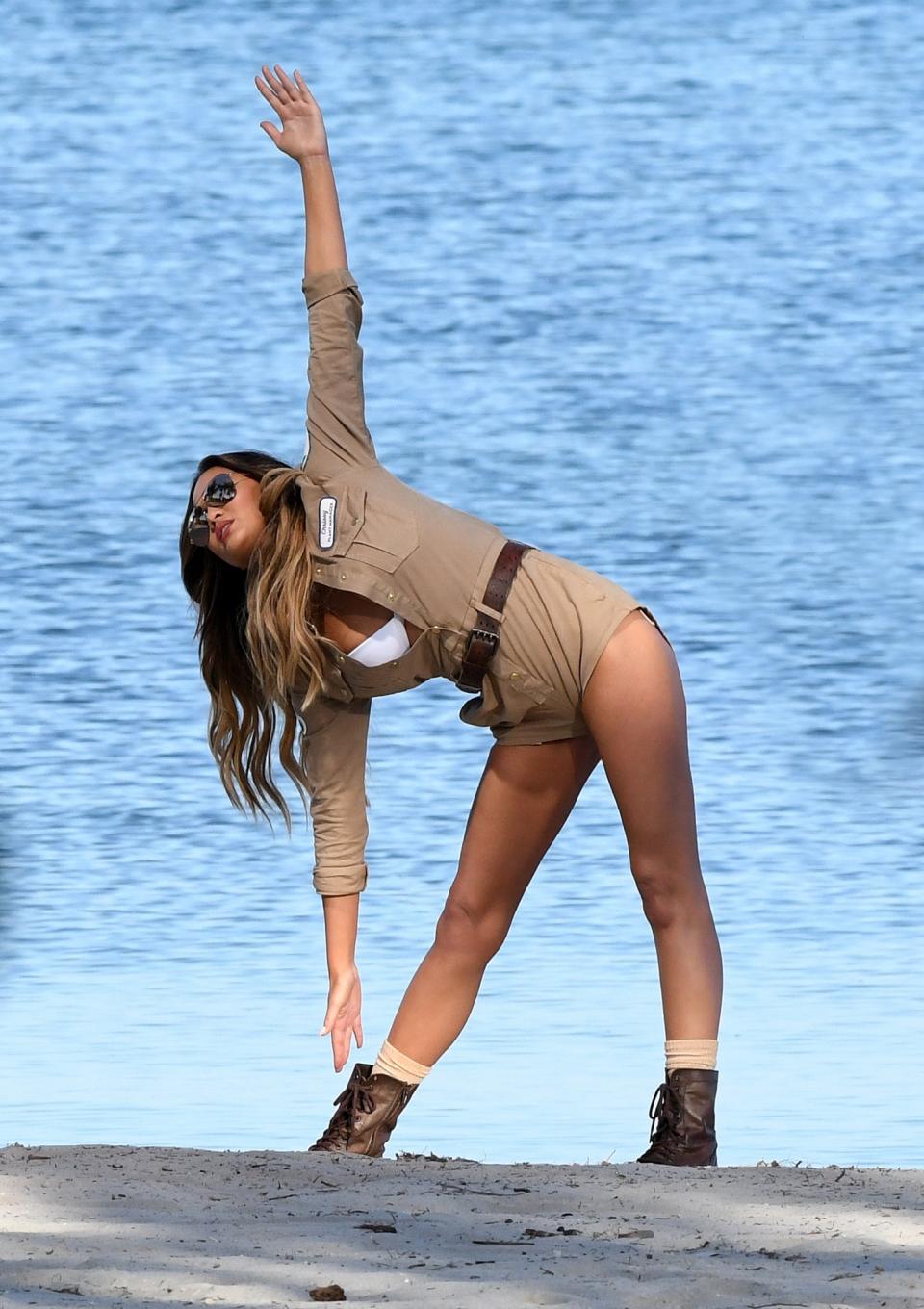 Chrissy Teigen stretches on the beach.