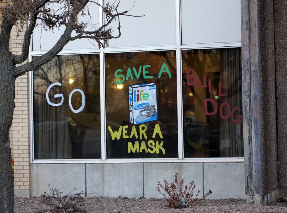 A sign on the Gove County Medical Center's nursing home reminds the public to wear a mask. Workers there painted the sign after a COVID-19 infection rampaged through the facility, killing 17 people.