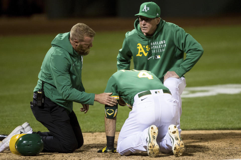 Oakland Athletics manager Bob Melvin, right, and head trainer Nick Paparesta, left, tend to Chad Pinder (4) after he was hit by a wild pitch by Los Angeles Angels relief pitcher Junior Guerra during the seventh inning of a baseball game in Oakland, Calif., Monday, June 14, 2021. (AP Photo/John Hefti)