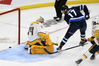 Winnipeg Jets' Adam Lowry (17) scores against Nashville Predators goaltender Juuse Saros (74) during the first period of NHL hockey game action in Winnipeg, Manitoba, Saturday, Oct. 23, 2021. (Fred Greenslade/The Canadian Press via AP)