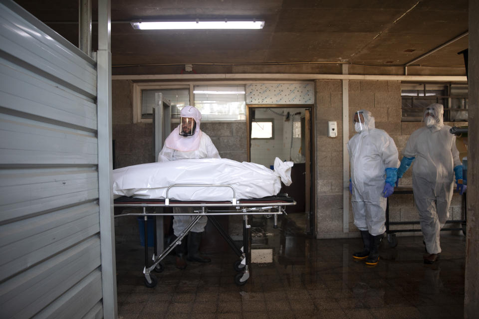 FILE - In this Sept. 23, 2020, file photo, workers from "Hevra Kadisha," Israel's official Jewish burial society, prepare a body before a funeral procession at a special morgue for COVID-19 victims in the central Israeli city of Holon, near Tel Aviv. The worldwide death toll from the coronavirus eclipsed 1 million, nine months into a crisis that has devastated the global economy, tested world leaders' resolve, pitted science against politics and forced multitudes to change the way they live, learn and work. (AP Photo/Oded Balilty, File)