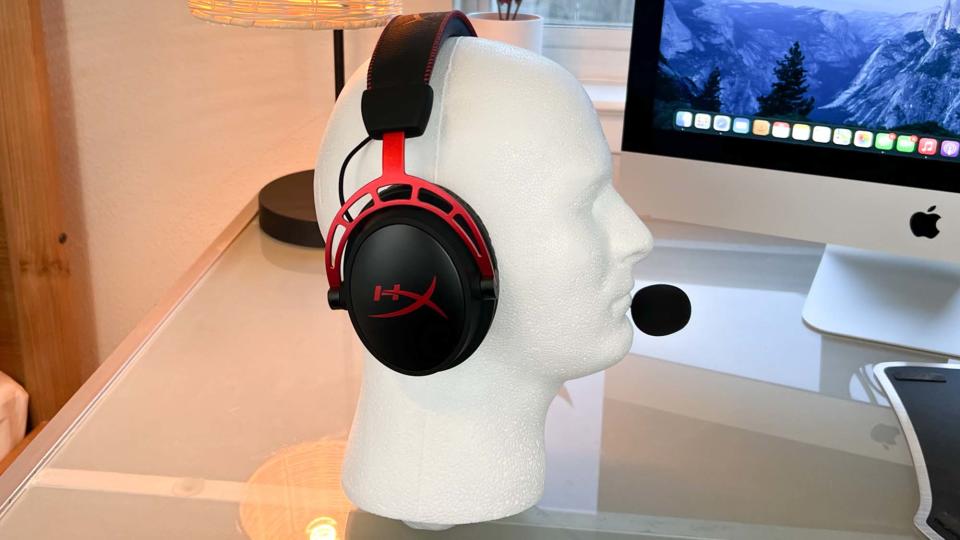 A HyperX Cloud Alpha Wireless gaming headset on a glass desk