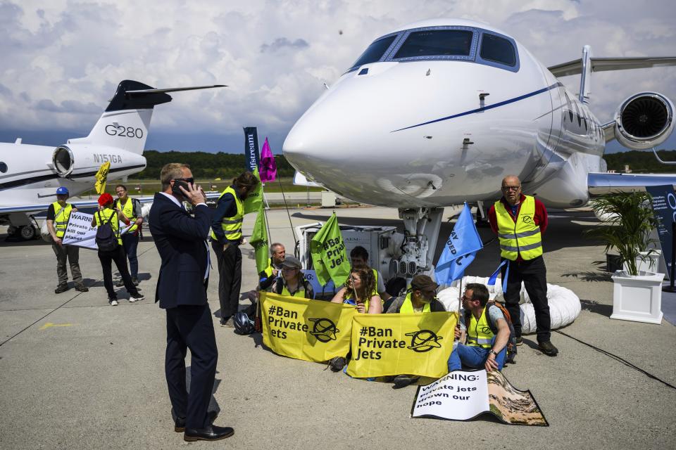 FILE - Environmental activists of Stay Grounded and Greenpeace demonstrate while handcuffing themselves to a plane during the European Business Aviation Convention and Exhibition (EBACE), at the Geneve Aeroport in Geneva, Switzerland, May 23, 2023. Climate activists have spraypainted a superyacht, blocked private jets from taking off and plugged holes in golf courses this summer as part of an intensifying campaign against the emissions-spewing lifestyles of the ultrawealthy. (Laurent Gillieron/Keystone via AP, File)