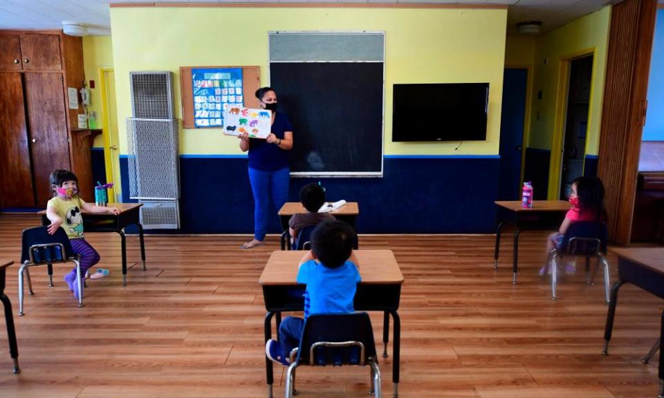 Instructor Chablis Torres reads to children in a pre-school class, wearing masks and at desks spaced apart as per coronavirus guidelines during summer school sessions at Happy Day school in Monterey Park, California, in July.