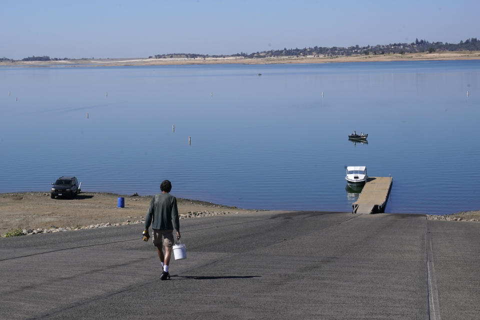 FILE - A man makes the long walk down the Folsom Lake boat ramp that is normally underwater in Folsom, Calif., Oct. 3, 2022. The reservoir is filled to about 70% of its historical average as California began its new water year that started Oct. 1. The impacts of climate change hit communities across the country, yet voters in rural areas are the least likely to feel Washington is in their corner on the issue. (AP Photo/Rich Pedroncelli, File)