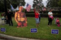 FILE PHOTO: Supporters of U.S. President Donald Trump display signs as the presidential motorcade passes by following a private fundraiser, in Longwood