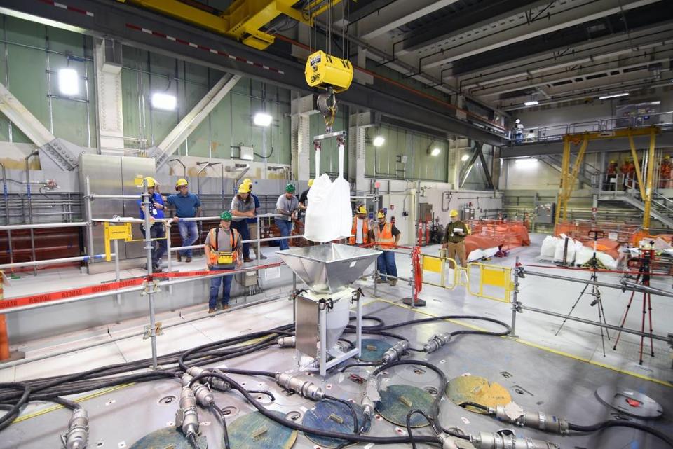 Workers at the Hanford site vitrification plant add frit, or glass beads, to the melter inside the Low-Activity Waste Facility.