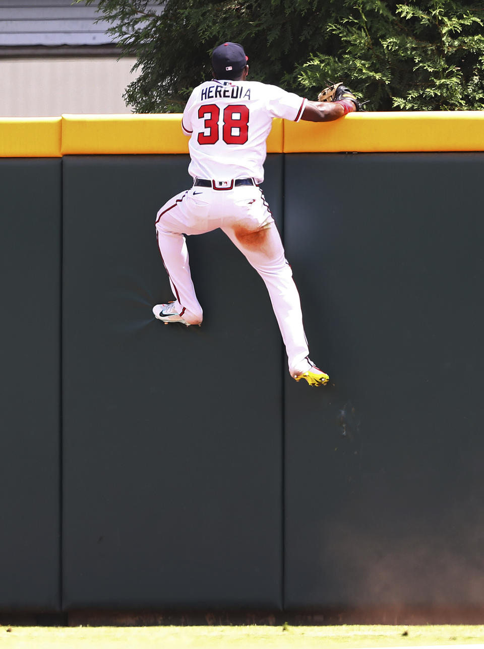 Atlanta Braves outfielder Guillermo Heredia climbs the wall but can't reach a three-run home run by Philadelphia Phillies Nick Castellanos during the eighth inning of a baseball game, Wednesday, Aug. 3, 2022, in Atlanta. (Curtis Compton/Atlanta Journal-Constitution via AP)