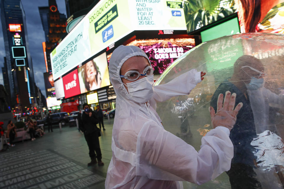 Artists perform under a billboard displaying information on COVID-19 in a sparsely populated Times Square, Friday, March 20, 2020, in New York. New York Gov. Andrew Cuomo is ordering all workers in non-essential businesses to stay home and banning gatherings statewide. "Only essential businesses can have workers commuting to the job or on the job," Cuomo said of an executive order he will sign Friday. Nonessential gatherings of individuals of any size or for any reason are canceled or postponed. (AP Photo/John Minchillo)