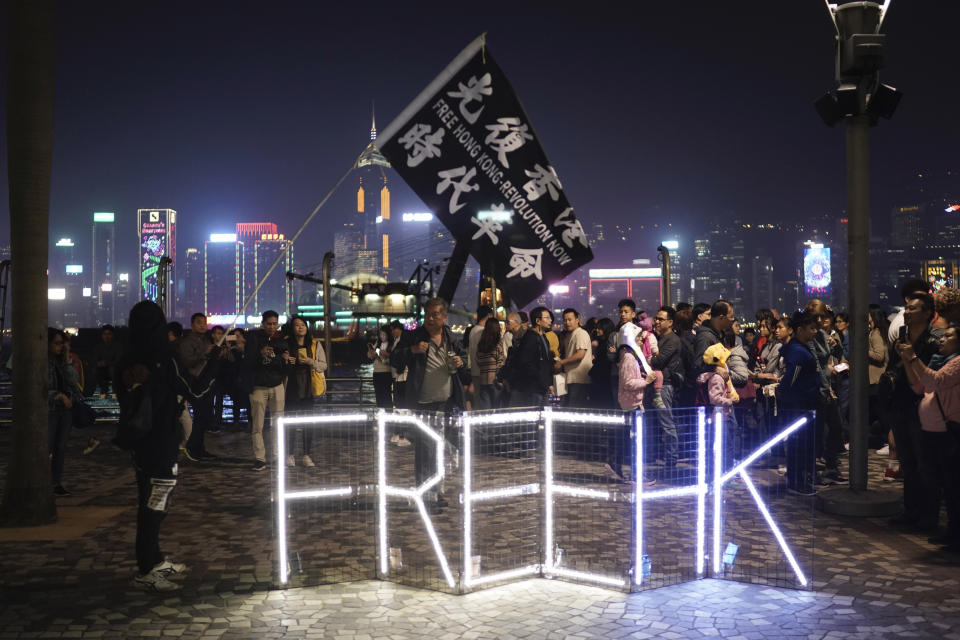 Protesters walk past a protest slogan during a rally on Christmas Eve in Hong Kong on Tuesday, Dec. 24, 2019. More than six months of protests have beset the city with frequent confrontations between protesters and police. (AP Photo/Kin Cheung)