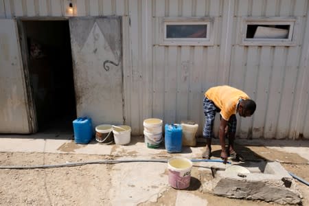 A Libyan man displaced from the town of Tawergha fills the bucket with water at a displaced camp in Benghazi