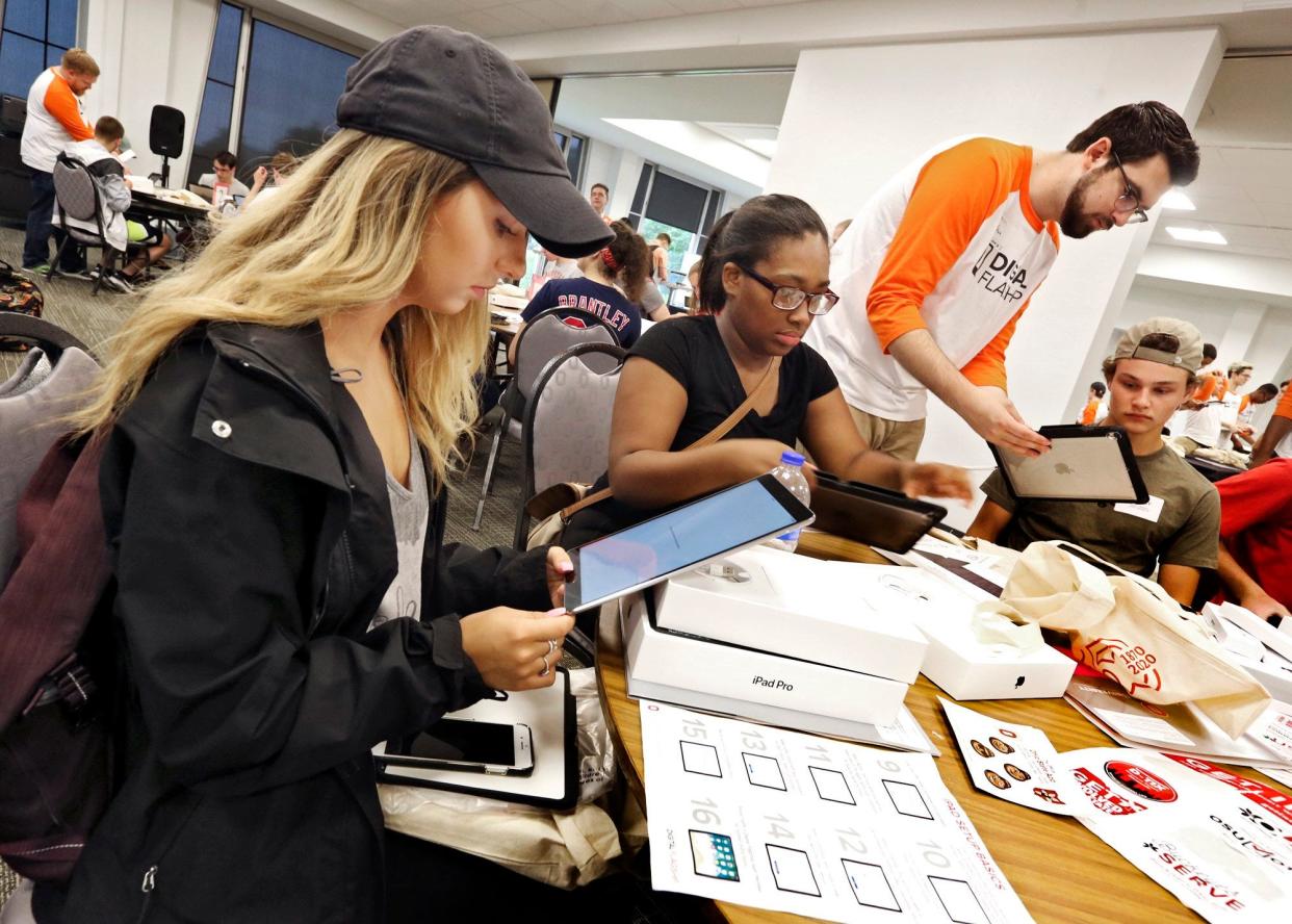 Left to right, sitting, Rylie Sines, of Grove City, Rayanna Drafton, of Columbus, and Bailey Evers, of Streetsboro, get help from student mentor Adam Edwards, standing, of West Chester, setting up their new iPads at the Drake Performance & Event Center at Ohio State University on June 12, 2018.