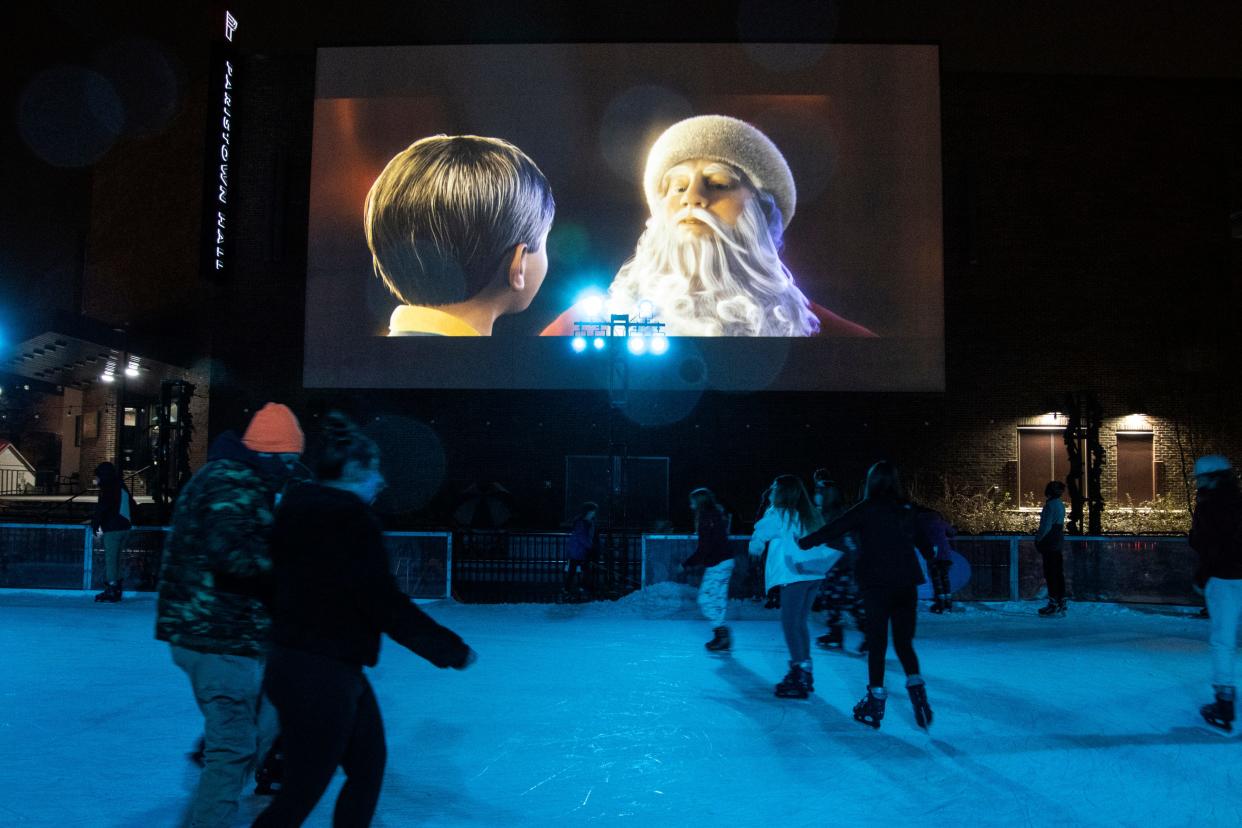 Skaters take to the ice on a rainy Saturday night in Paristown as the movie The Polar Express looms large on a cinema screen during the annual Fete de Noel Winter Holiday Festival. 12/19/20