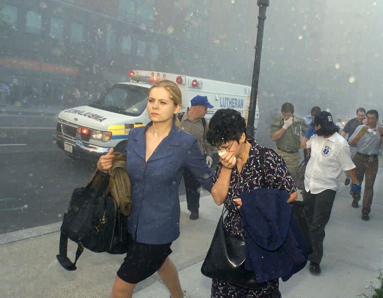 Las personas se cubren la cara de la lluvia de polvo y escombros cuando abandonan el área del ataque al World Trade Center de Nueva York, el martes 11 de septiembre de 2001