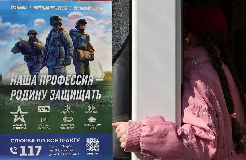 FILE PHOTO: A customer enters a shop with a poster promoting Russian army service in Moscow