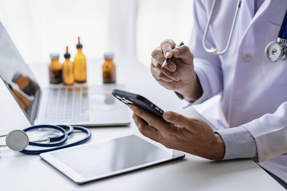 Doctor usando un celular con la app de tecnología sobre medicina, para consultar a un paciente online. Foto: Getty