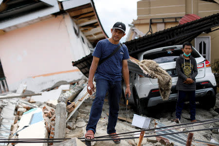 Government district officer, Yassir Garibaldi, 43, stands in front of his parents' destroyed house hit by an earthquake, in Balaroa neighbourhood, Palu, Central Sulawesi, Indonesia, October 11, 2018. REUTERS/Jorge Silva