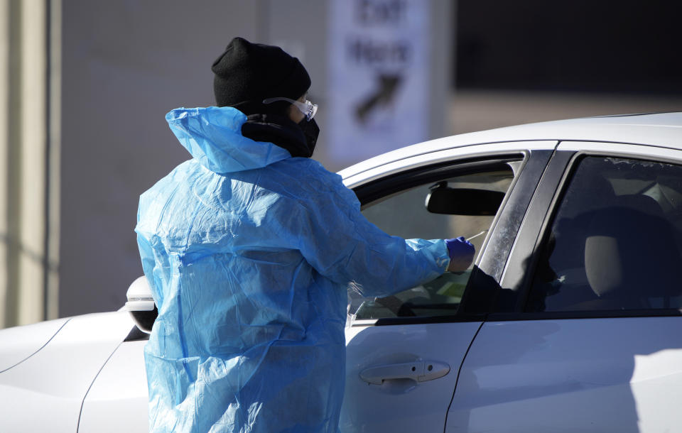 FILE - A medical technician performs a nasal swab test on a motorist queued up in a line at a COVID-19 testing site near All City Stadium Dec. 30, 2021, in southeast Denver. Millions of workers whose jobs don’t provide paid sick days are having to choose between their health and their paycheck as the omicron variant of COVID-19 rages across the nation. While many companies instituted more robust sick leave policies at the beginning of the pandemic, those have since been scaled back with the rollout of the vaccines, even though the omicron variant has managed to evade them. (AP Photo/David Zalubowski, File)