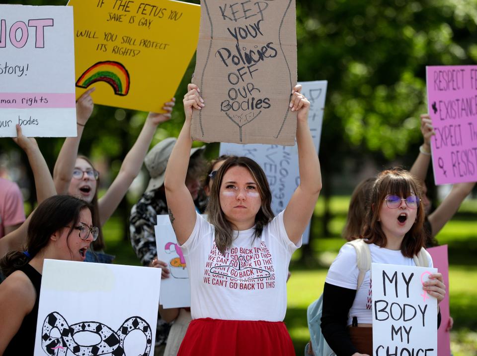 Carissa Kissinger, center, holds a sign while standing along Mason Street on June 29, 2022, in Green Bay, Wis., to protest the Supreme Court overturning Roe v. Wade, which made abortion a constitutional right for nearly 50 years.