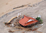 <p>In this aerial image, police officers surround a house buried by a mudslide after the torrential rain on July 6, 2017 in Asakura, Fukuoka, Japan. (Photo: The Asahi Shimbun via Getty Images) </p>