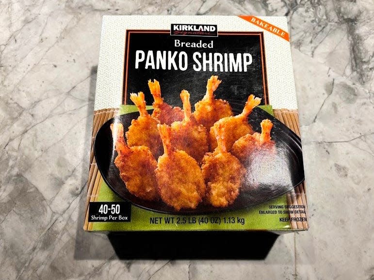 A box of breaded panko shrimp with image of shrimp on a black plate and a black label