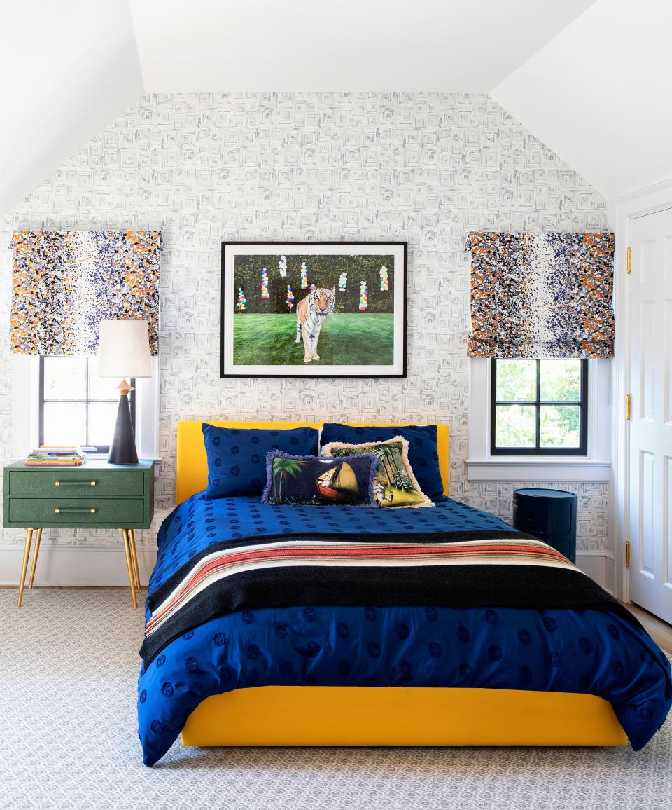 A son’s bedroom features a playful yellow bed by Bludot. The colorful window coverings, by Pierre Frey, and eccentric artwork, by Gray Malin, further enhance the fun spirit of the room. The night tables are by Made Goods, and the rug is by Stark.