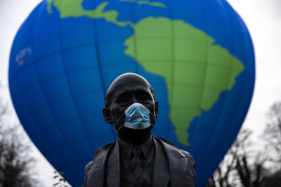 The bust of French statesman Robert Schuman, one of the founders of the European Union, is seen while environmental activists launch a hot air balloon during a demonstration outside of an EU summit in Brussels, Thursday, Dec. 10, 2020. European Union leaders meet for a year-end summit that will address anything from climate, sanctions against Turkey to budget and virus recovery plans. Brexit will be discussed on the sidelines. (AP Photo/Francisco Seco)