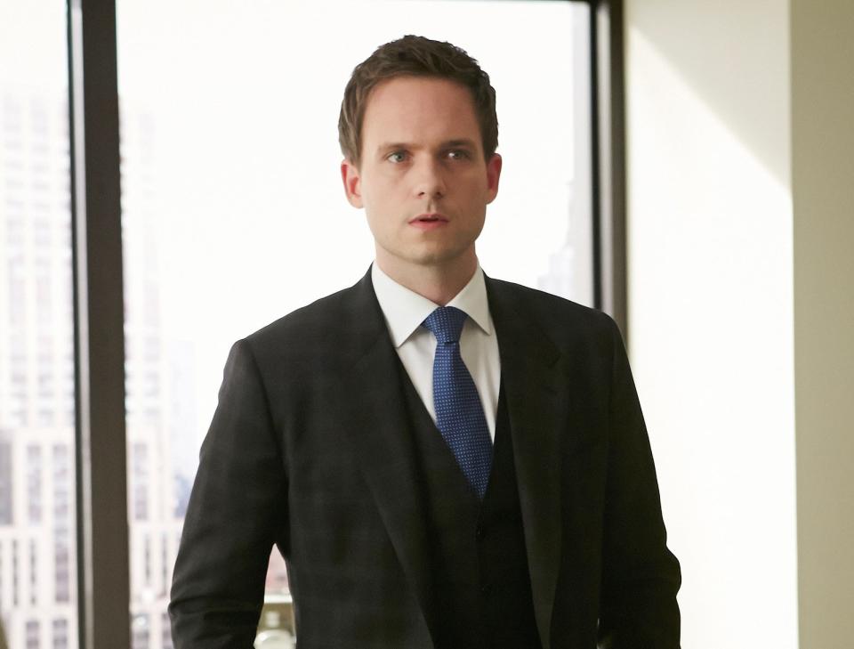 Patrick J. Adams as Mike Ross in "Suits," wearing a tailored suit and tie, standing in an office setting