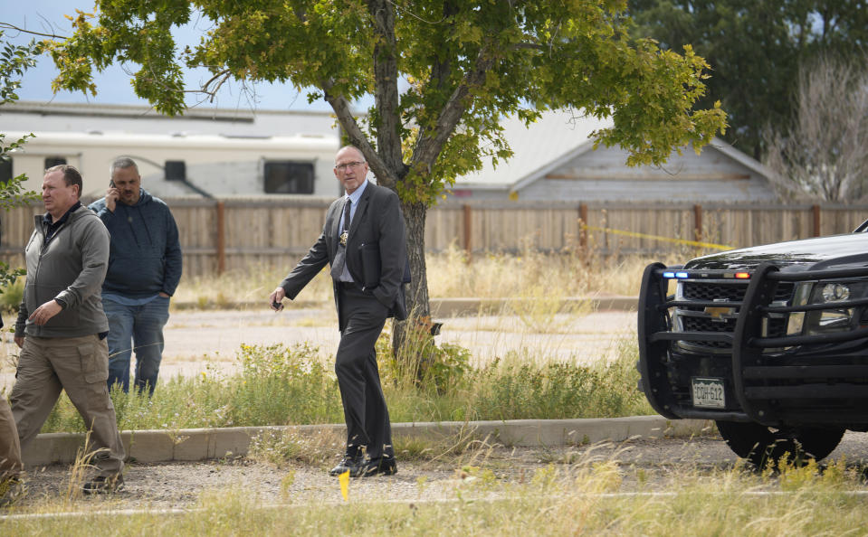 Fremont County, Colo., coroner Randy Keller, center, surveys the grounds with fellow authorities outside a closed funeral home where 115 bodies have been stored, Friday, Oct. 6, 2023, in Penrose, Colo. Authorities are investigating the improper storage of human remains at the southern Colorado funeral home that performs "green" burials without embalming chemicals or metal caskets. (AP Photo/David Zalubowski)